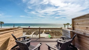 A wooden deck with two Adirondack chairs facing a beach with a clear view of the ocean and a sandy shore. - Beachside 8W - 3BD Gulf-Front Townhome, 2 Decks, Sleeps 10 (Panama City Beach)