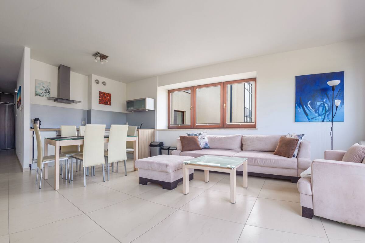 Ein modernes Wohnzimmer mit Sofa, Couchtisch und Essbereich.