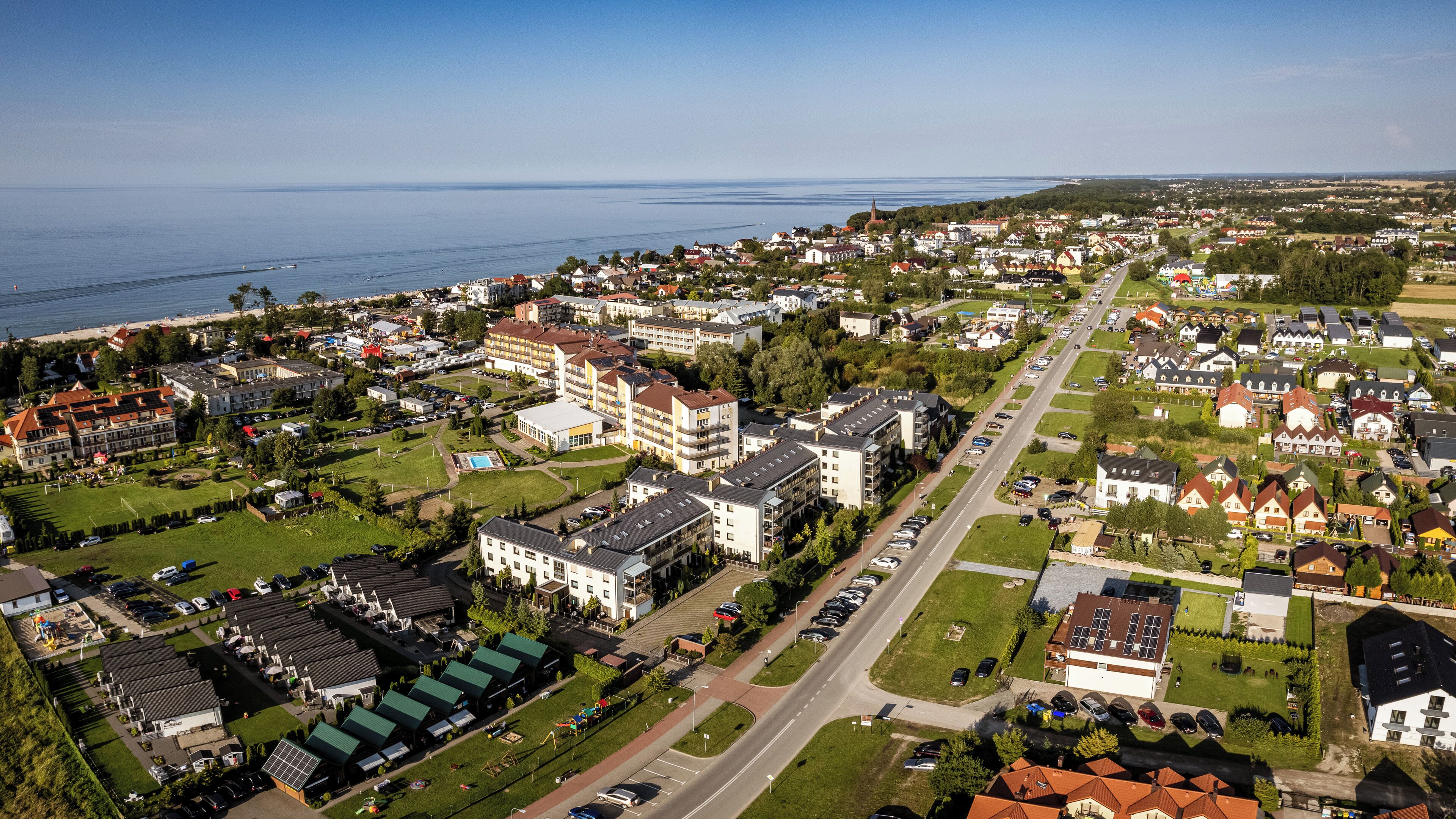 Un quartier résidentiel composé d’un mélange de maisons unifamiliales et d’immeubles d’appartements, avec une rue principale et une étendue d’eau en arrière-plan.