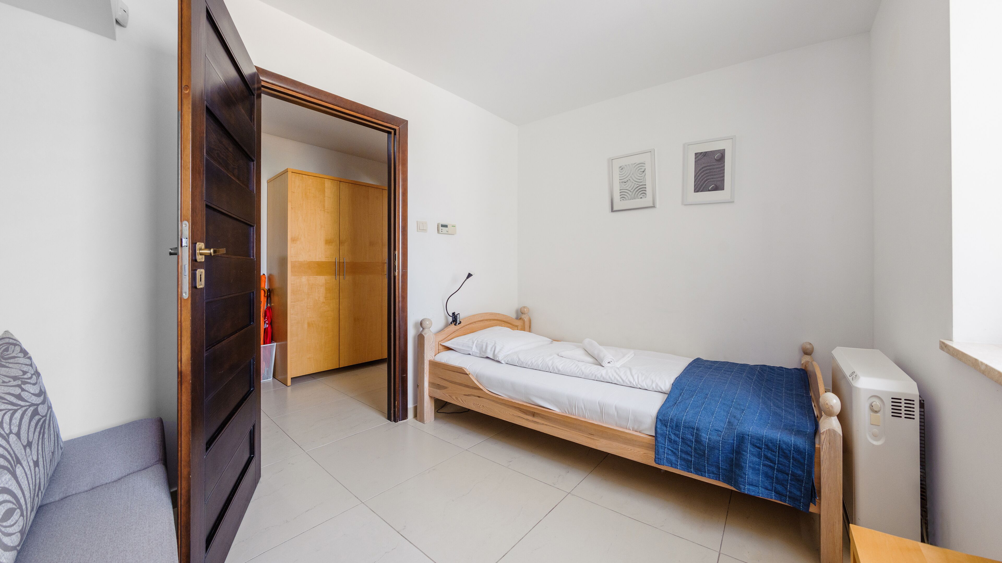 A small, clean room with a bed, a desk, a chair, and a wardrobe.