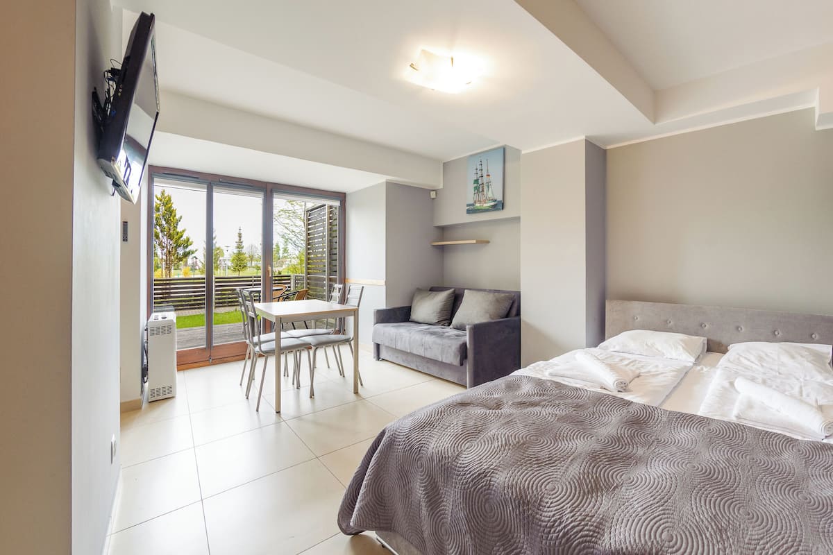 Ein modernes Hotelzimmer mit Balkon, einer Sitzecke, einem Esstisch und einem Bett.