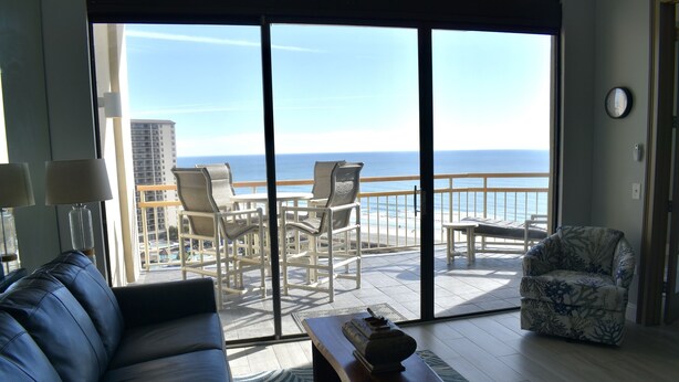 A living room with a view of the ocean, a sofa, a coffee table, and a chair. - One of a Kind Penthouse--All New! A Beach Lover's Dream Vacation Rental+Locker!! (Myrtle Beach)