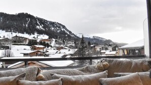 Quarto aconchegante com vista para uma vila montanhosa coberta de neve.