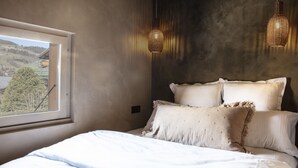 A bedroom with a large window, a bed with white linens, and two hanging light fixtures. - Apartment FERRONNE by JAPANDI home (Megève)