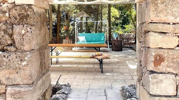 An outdoor seating area with stone walls and a covered section.
