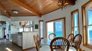 A spacious dining area with a wooden ceiling and large windows offering a view of the ocean.
