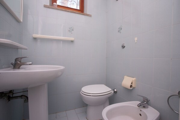 A bathroom with a sink, toilet, and bidet.