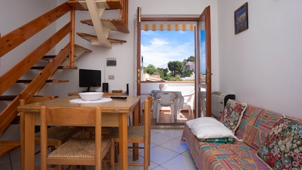 A room with a wooden staircase, a dining table with chairs, a sofa, and a view through an open door. - M291 - Marcelli, apartment with terrace and reserved parking (Marcelli)