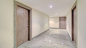 Ein Korridor mit Marmorboden, Holztüren und eingelassener Deckenbeleuchtung.