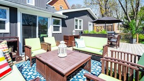 Une terrasse avec des meubles d’extérieur, un barbecue et un grand parasol.