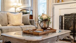 Un salon avec un canapé, une table basse sur laquelle se trouve un plateau, et un vase rempli de fleurs.