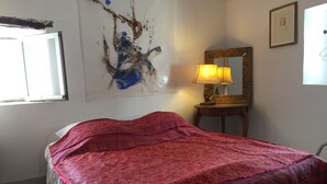 A bedroom with a bed, a lamp, a mirror, and a painting on the wall. - Maison D'artiste Atypique (Saint-Hippolyte-du-Fort)