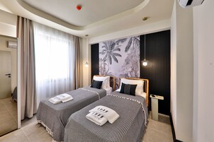 Habitación de hotel con dos camas, un ventanal con cortinas, aire acondicionado instalado en la pared y una lámpara en el techo.