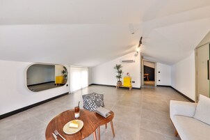 Una sala de estar moderna con una mesa redonda de madera, un sofá y un espejo.