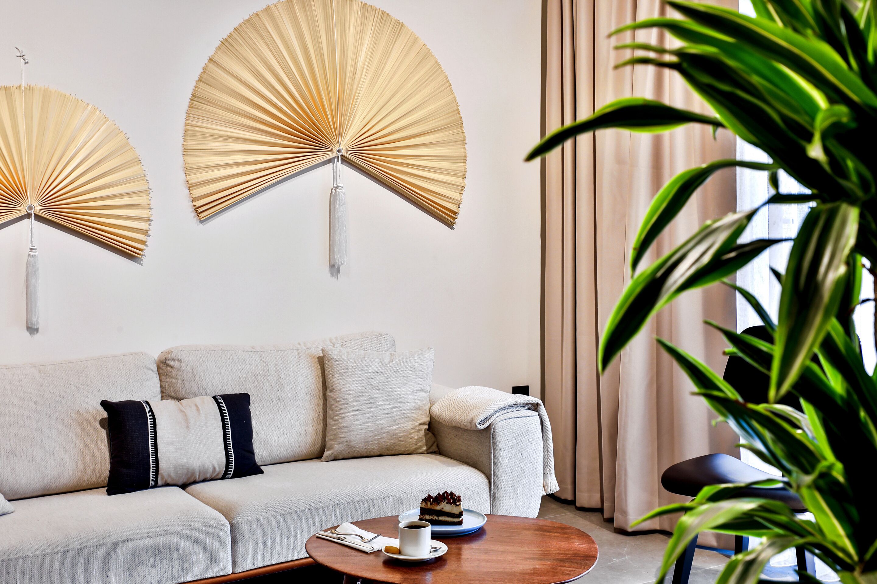 A modern living room with a sofa, two wall-mounted fans, a coffee table with a cake, and a potted plant.