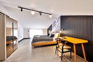 Un dormitorio moderno con cama, escritorio y espejo.