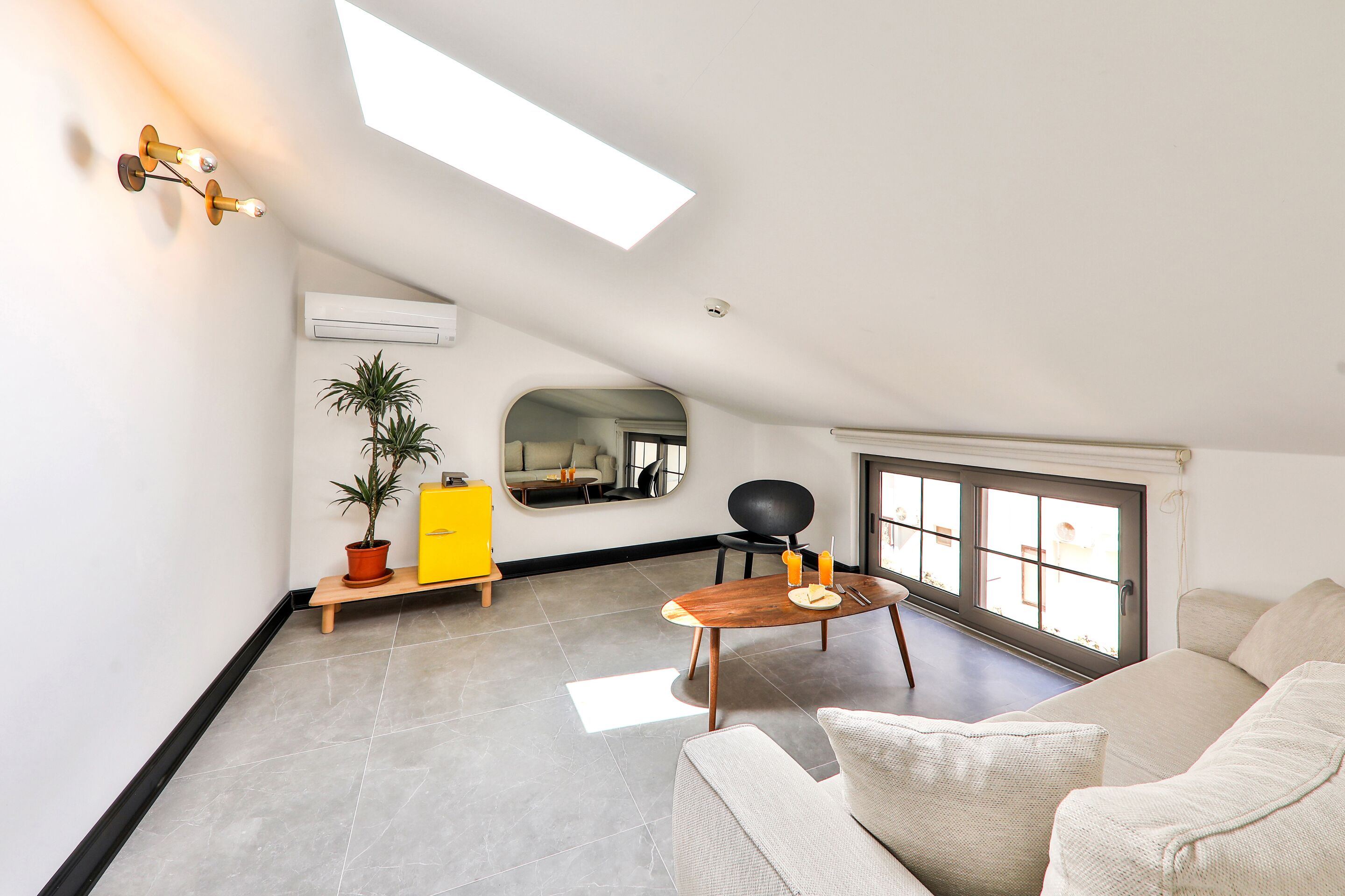 A modern living room with a skylight, a dining area, and a large window.