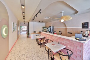 Un interior de restaurante moderno con una barra larga, zona de estar y un ventilador de techo.