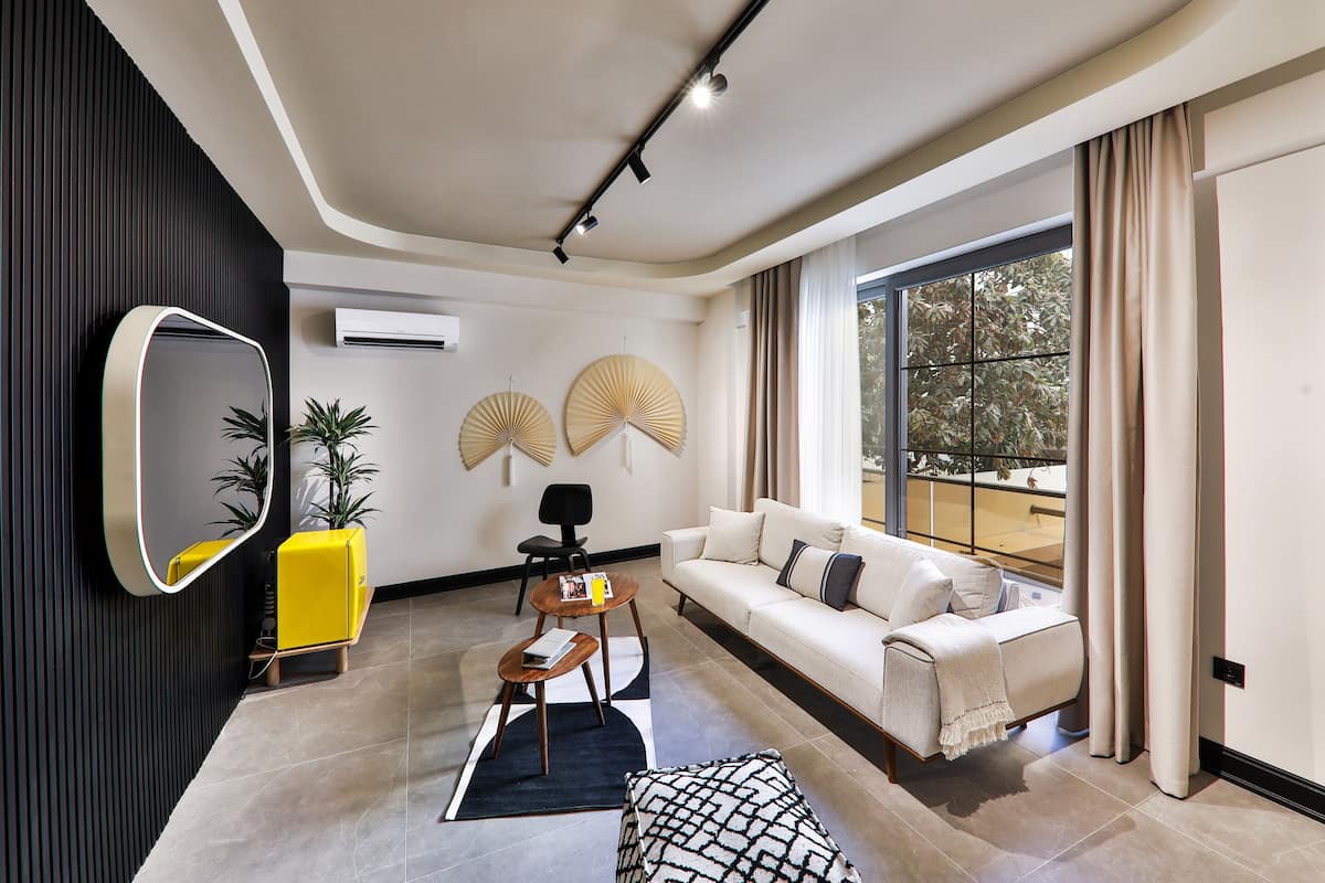 Una sala de estar moderna con un sofá, una mesa de centro, un espejo y ventiladores decorativos.