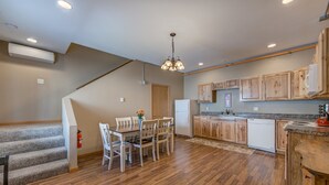 Eine Küche mit Holzausstattung, einem Esstisch mit Stühlen, einem Kühlschrank und einer Treppe.