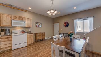 A kitchen with wooden cabinets, a white stove, and a dining area with a wooden table and white chairs.