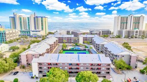 A multi-story hotel with a central courtyard, outdoor pool, and a view of the ocean. - Stay at Tilghman Beach & Racquet Club 241 a second-row 3BR condo just steps from the sand with two balconies, pools, and tennis courts. (North Myrtle Beach)