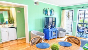 A dining area with a wooden table, blue placemats, and wicker chairs. - Stay at Tilghman Beach & Racquet Club 241 a second-row 3BR condo just steps from the sand with two balconies, pools, and tennis courts. (North Myrtle Beach)