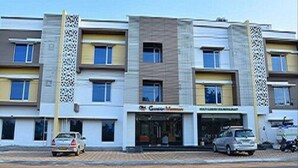 A multi-story building with a modern architectural design, featuring a central entrance with glass doors and signage for a restaurant. - Ganesh Meridian (Tiruppattur)