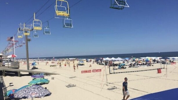 Una playa con una torre de salvavidas, sombrillas y un cielo despejado.