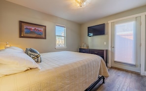 Un dormitorio con cama, cómoda, televisor y puerta.