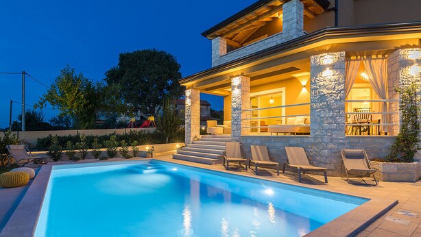 A swimming pool with lounge chairs and a stone exterior.