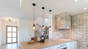A modern kitchen with a wooden island, white cabinetry, a built-in oven, and a patterned backsplash.