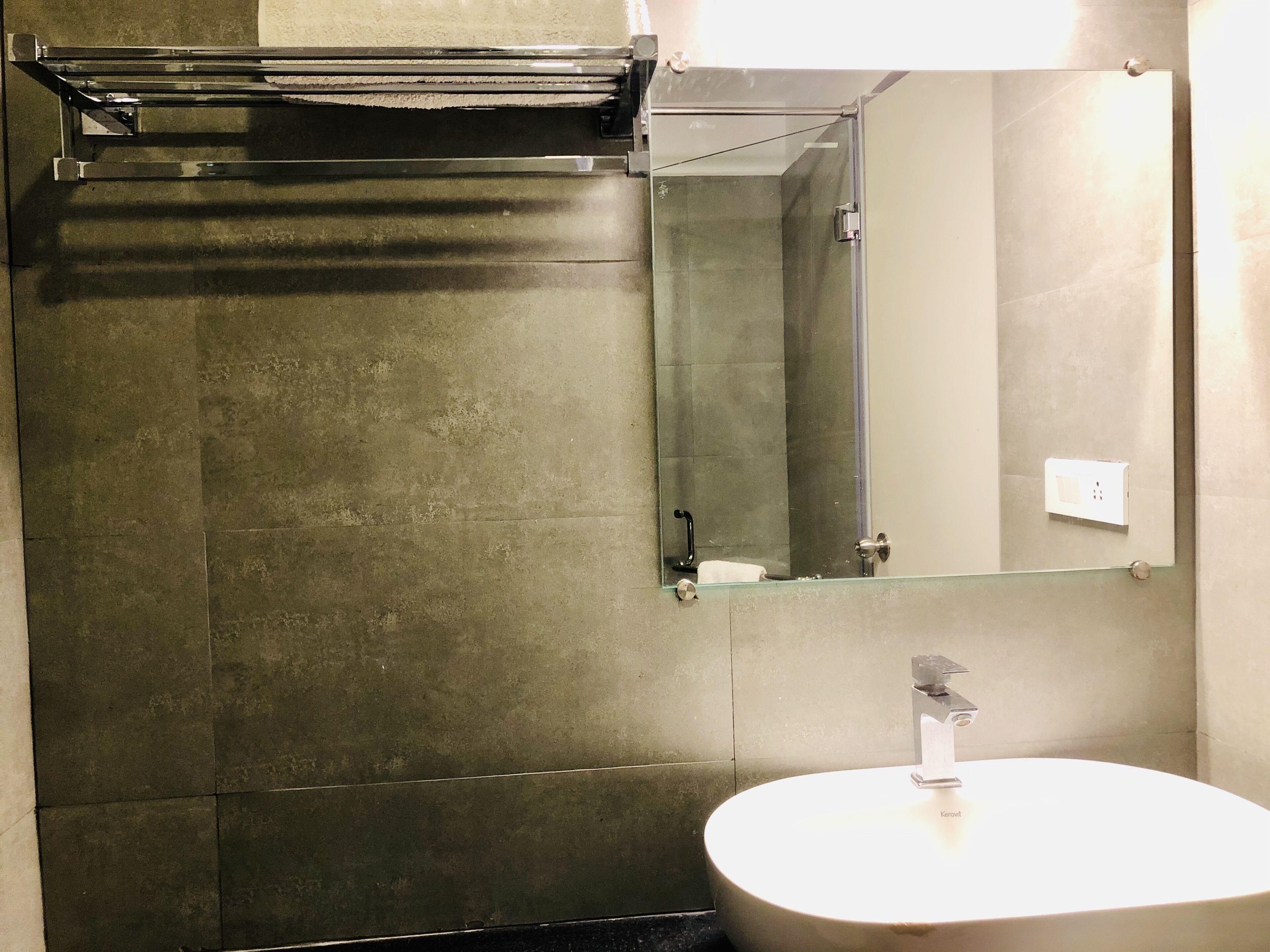 A bathroom with a glass shower enclosure, a sink with a modern faucet, and a mirror.