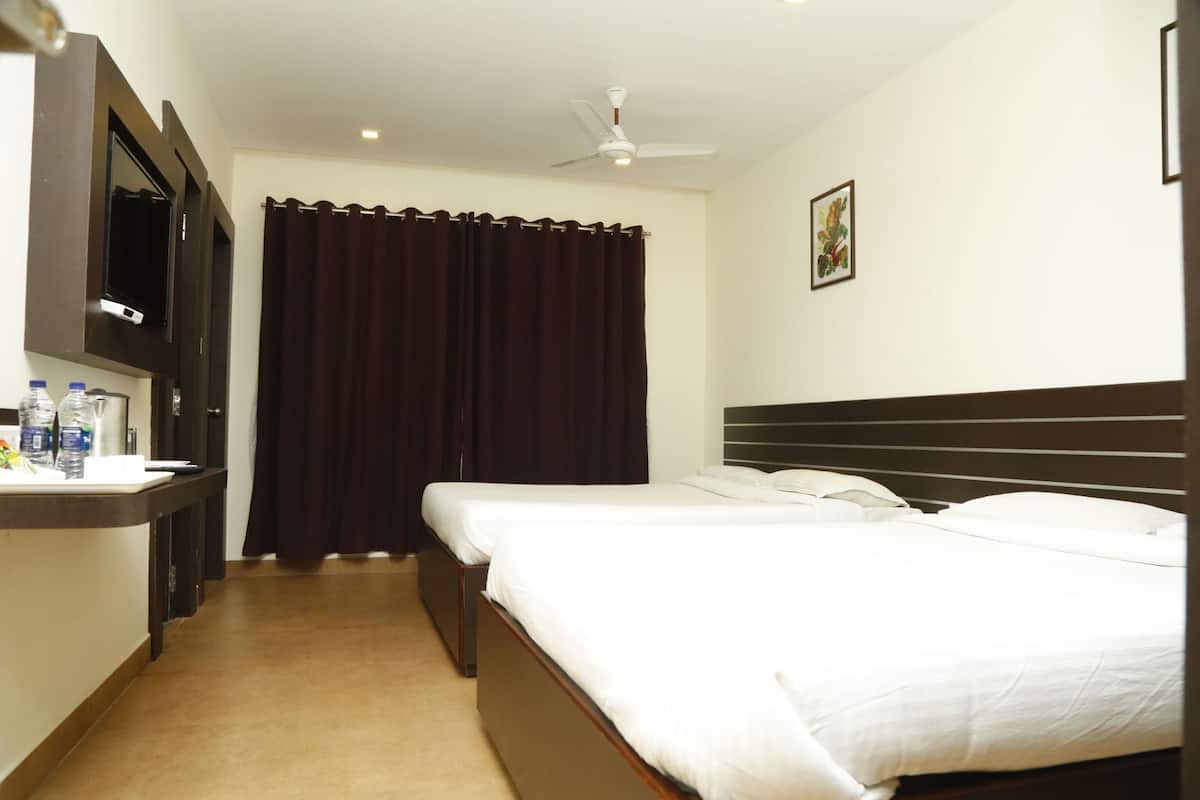 A hotel room with a bed, a bedside table, a mirror, a ceiling fan, and a curtain.