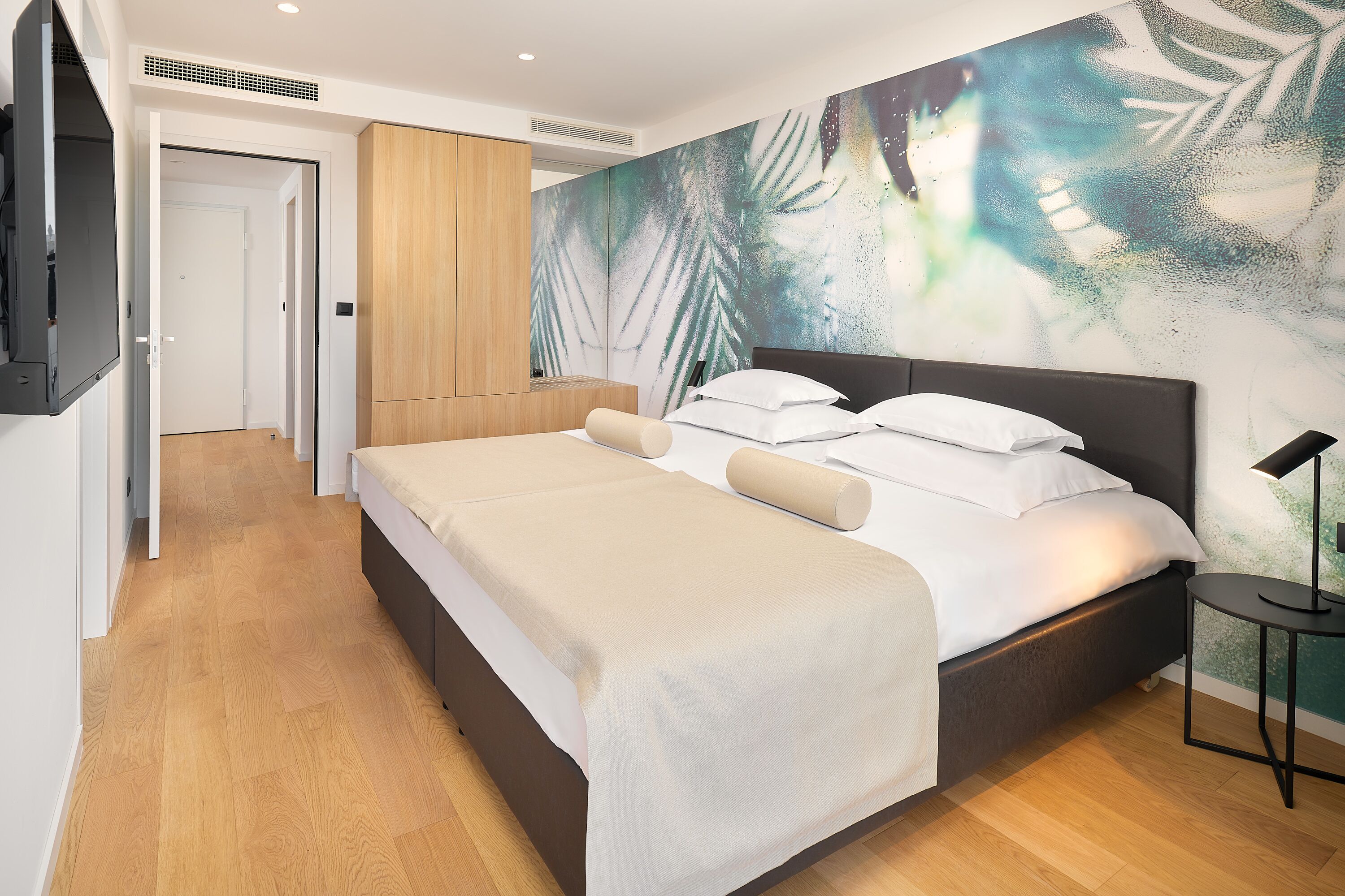 A modern bedroom with a bed, a wooden wardrobe, and a large wall mural.