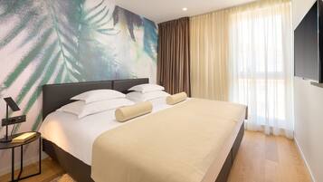 A modern hotel room with a large bed, a flat-screen TV, and a wall mural.