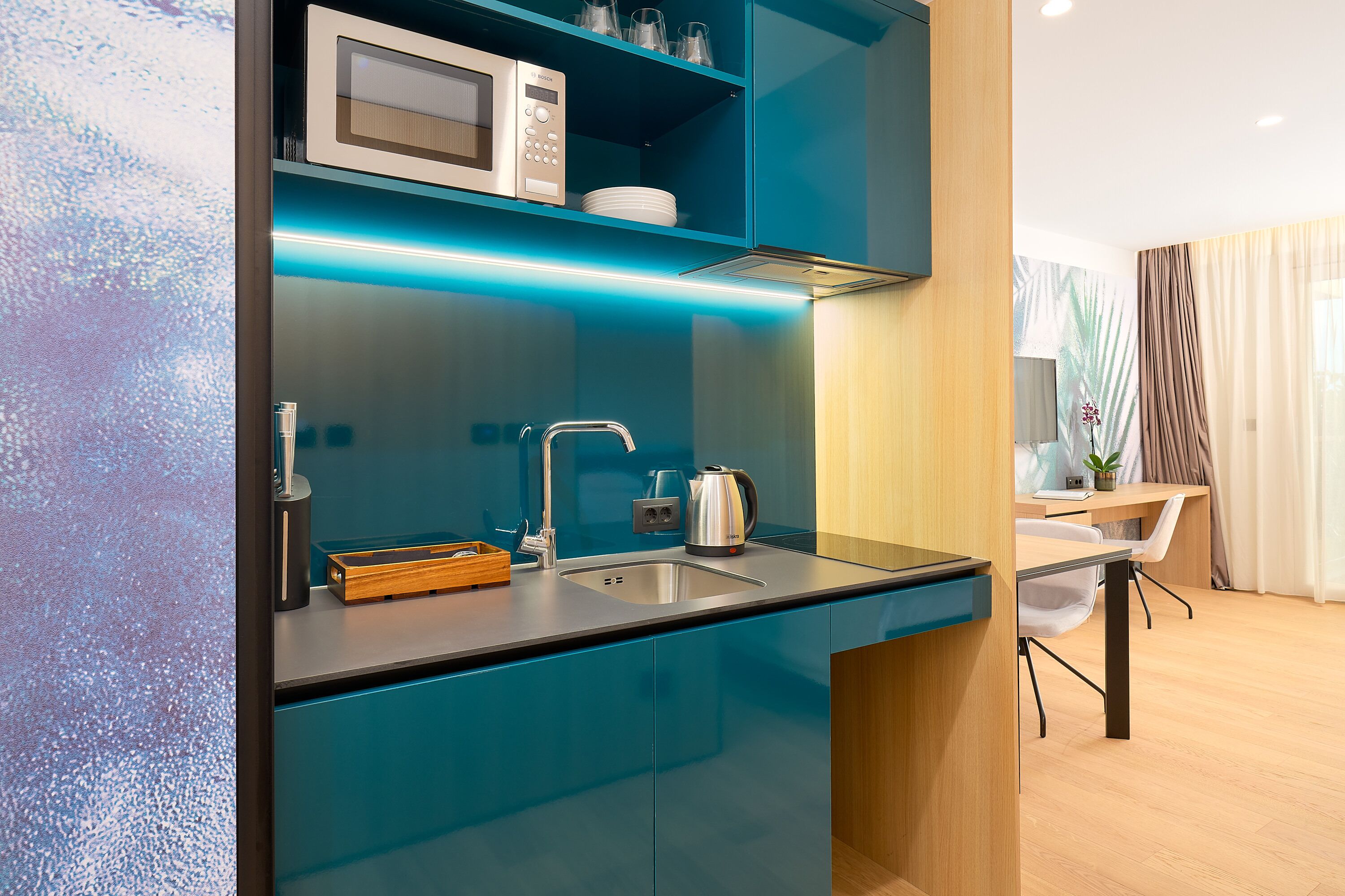 Una cocina moderna con microondas integrado, hervidor y pileta.