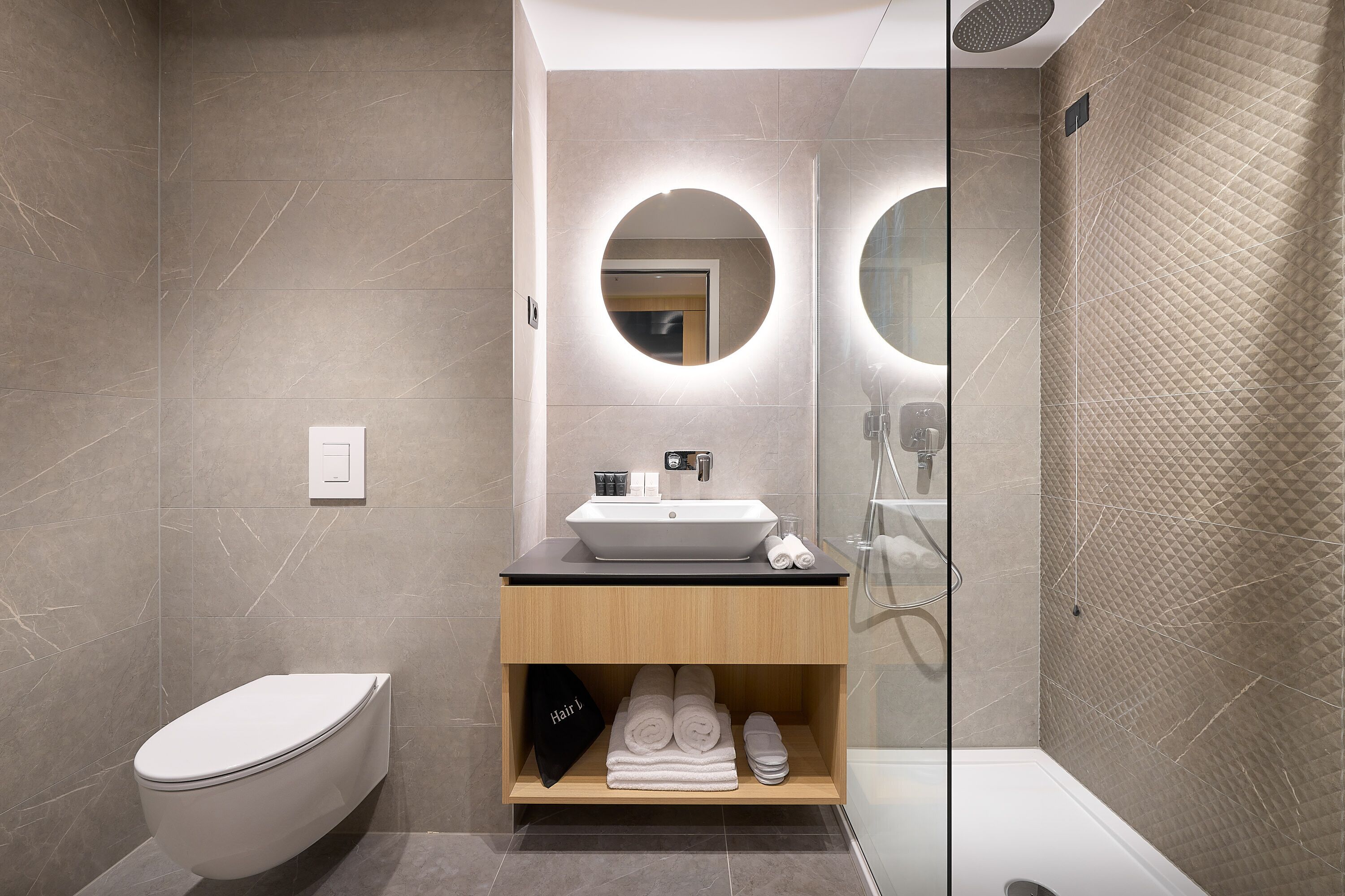 Et stilfuldt badeværelse med toilet, vaskebord med vask og en bruseniche.