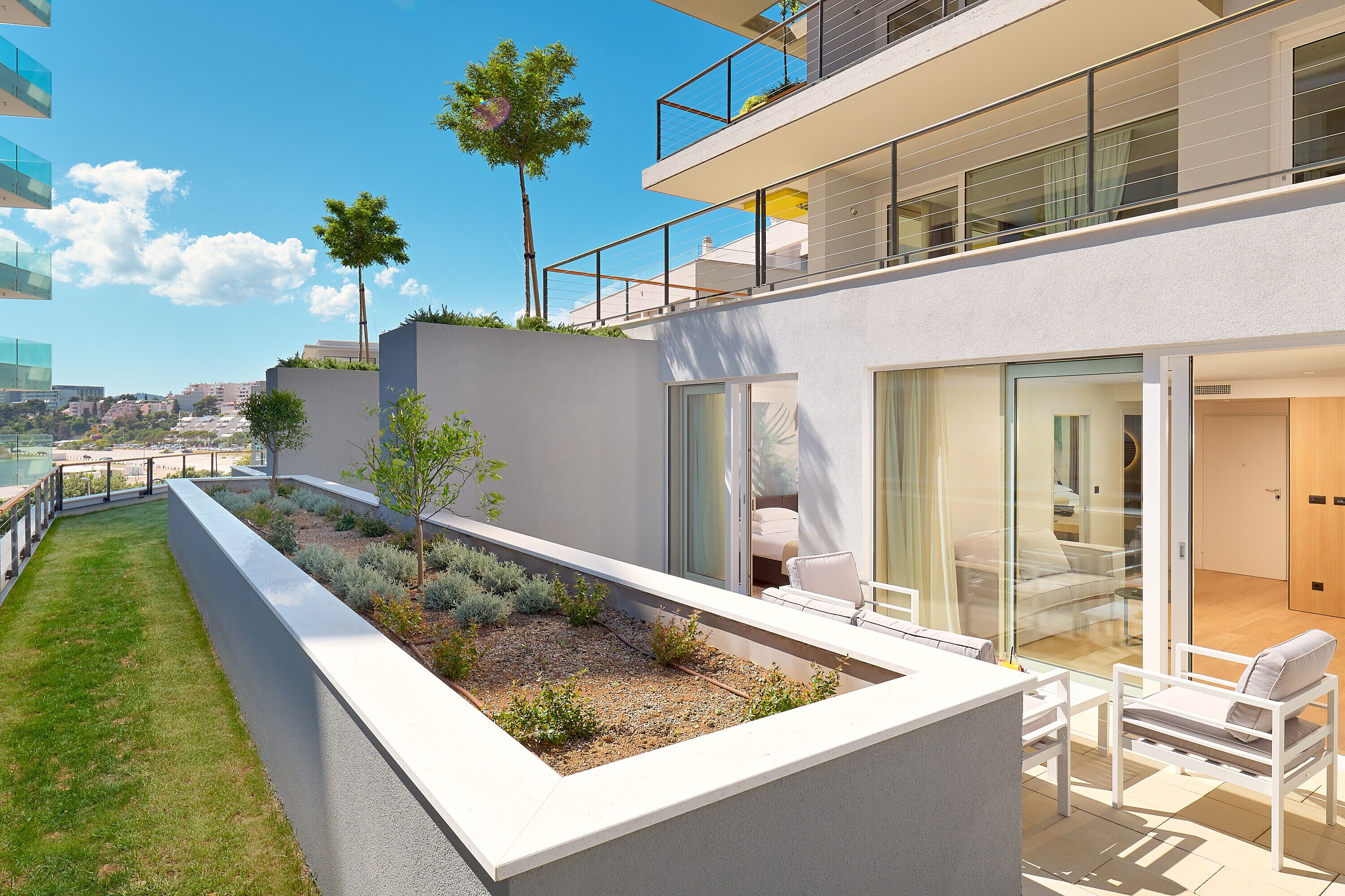 Un appartement moderne doté d’un balcon, d’un petit jardin et offrant une vue sur la ville.