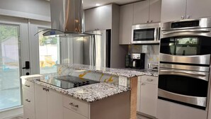 A modern kitchen with stainless steel appliances, a granite countertop, and a built-in oven.