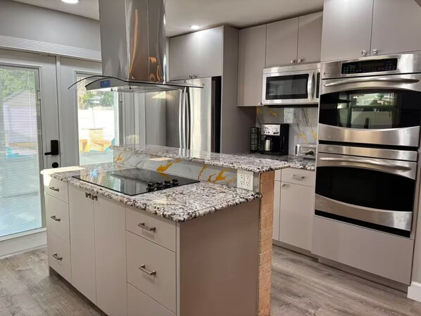 A modern kitchen with stainless steel appliances, a granite countertop, and a built-in oven.