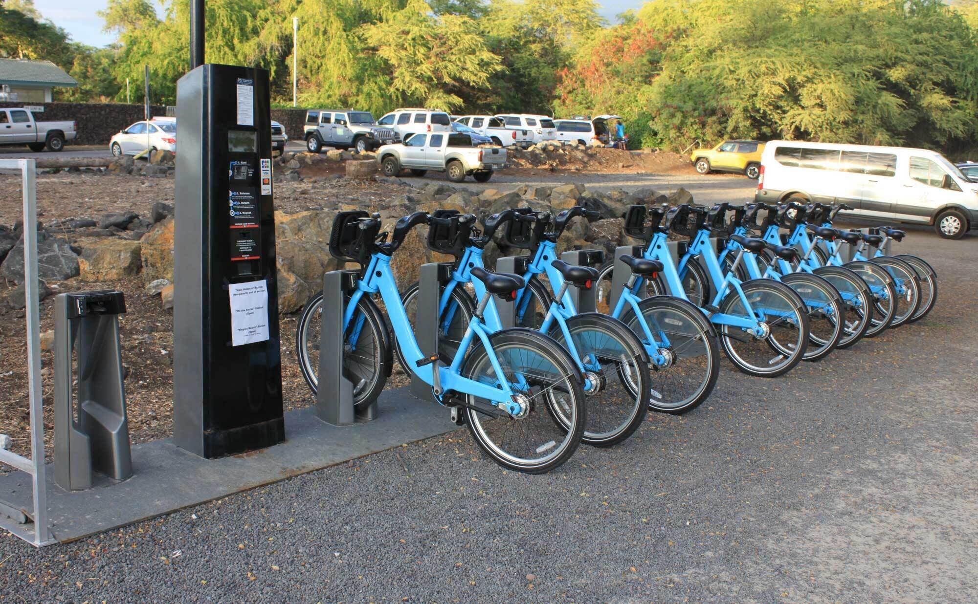 Una estación de alquiler de bicicletas con varias bicicletas y un quiosco de pagos.