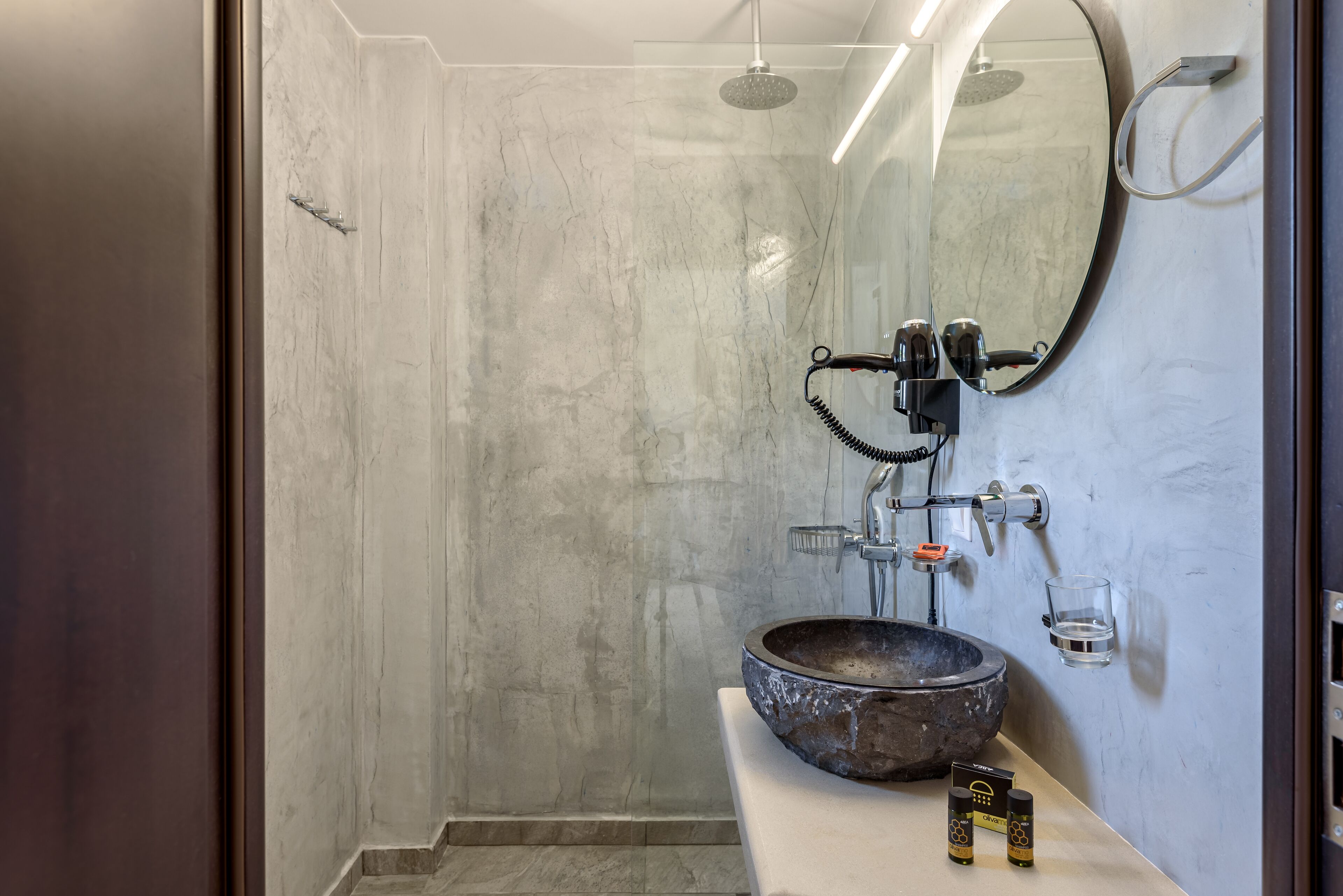 A modern bathroom with a large mirror, a round sink, and a shower.