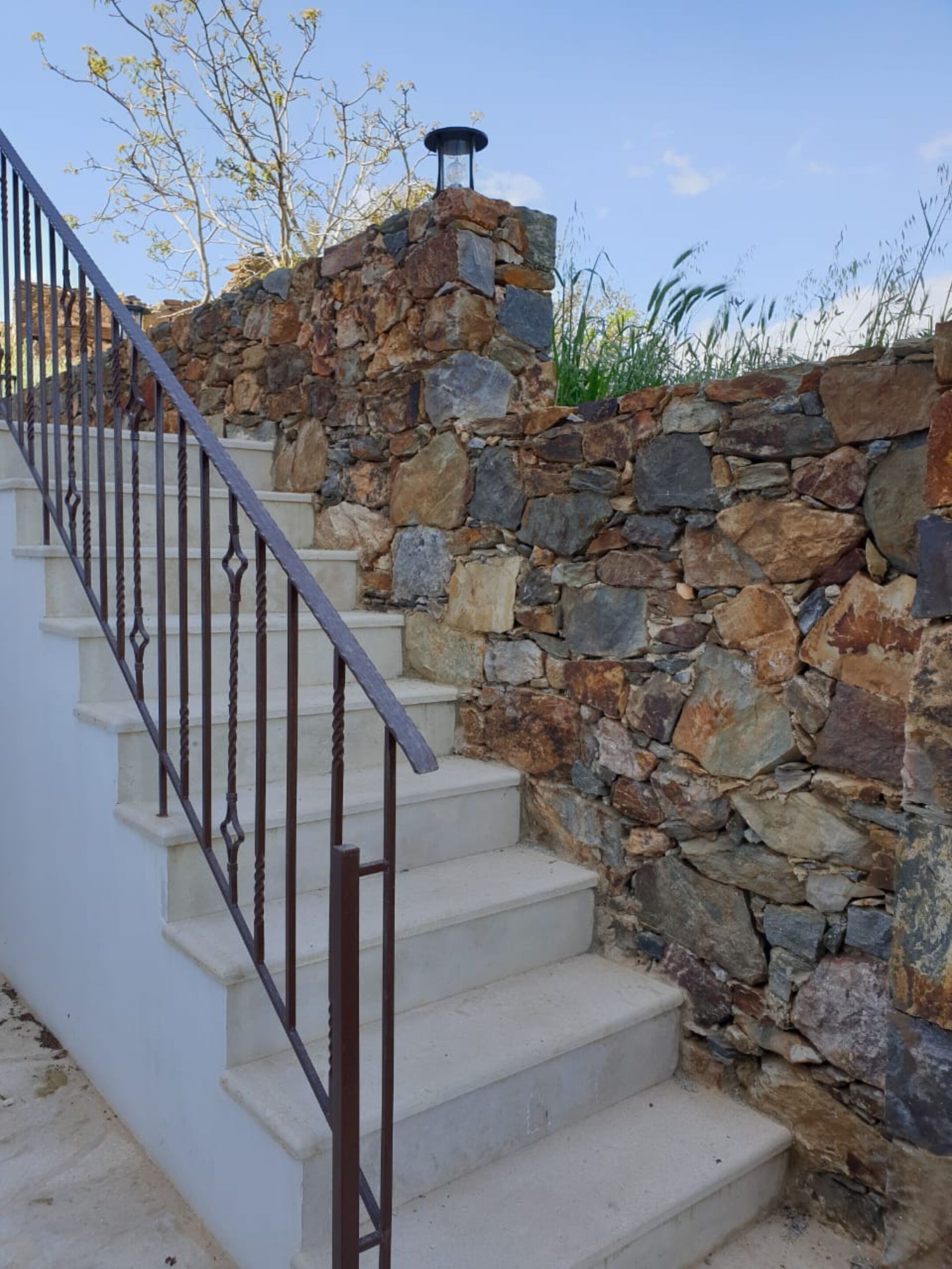 Un escalier avec des murs en pierre et une rampe en métal.