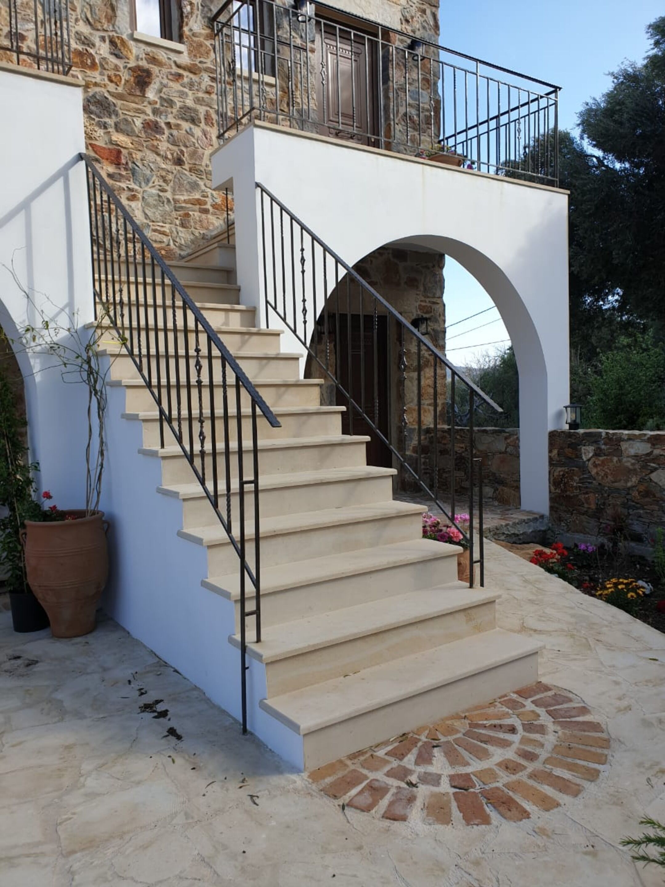 A staircase leading to a balcony with stone walls and a potted plant beside it.