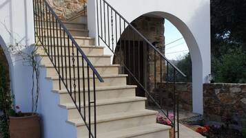 A staircase leading to a balcony with stone walls and a potted plant beside it.