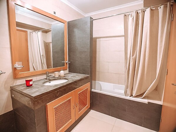 Une salle de bain équipée d’un lavabo, d’un miroir, d’un meuble de rangement, d’une douche et d’une baignoire.