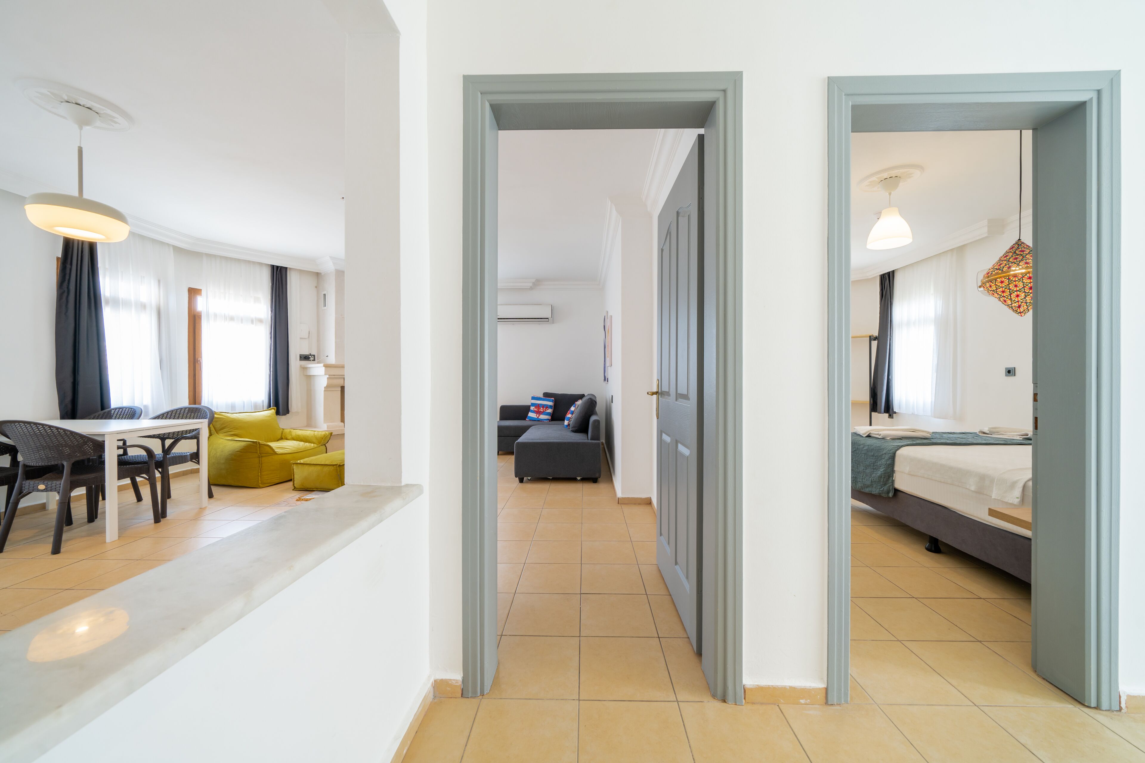 Una habitación de hotel moderna con cama, escritorio y sofá. Se ve un pasillo que conduce a otra habitación.