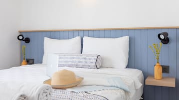 Cozy retreat with a bed, wall-mounted lamps, and a small shelf with a vase and plant.