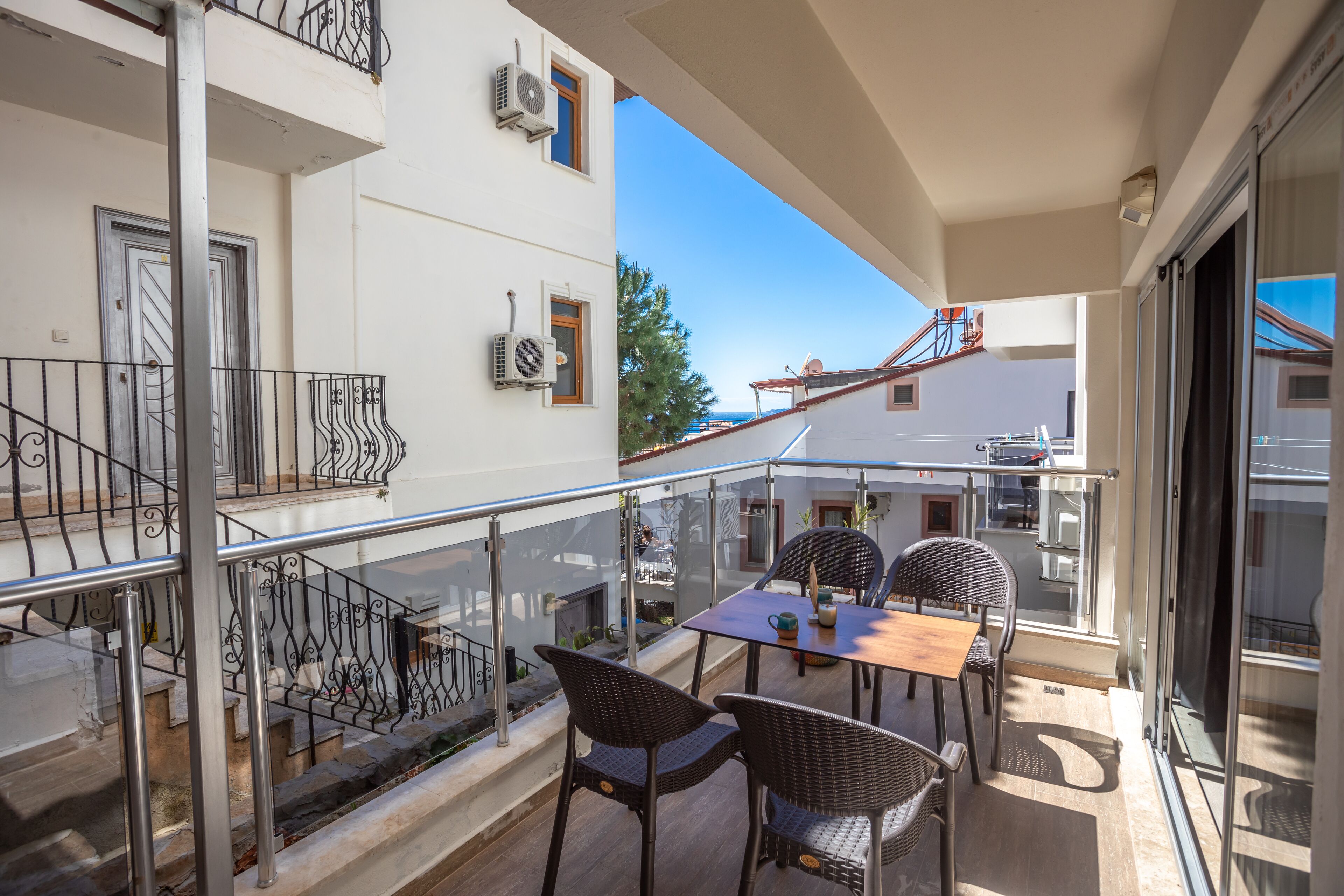 A balcony with a table and chairs, a railing, and a view of the street.